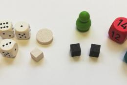 Bílé kostky a žetony nepřátel, zelená figurka barda, černé kostky síly a speciální barevné kostky